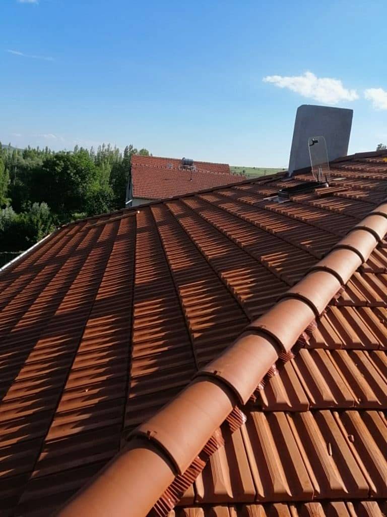 Kiremit Çatı Nasıl Gerçekleştirilir? Kiremit, toprağın pişirilmesi sonucunda elde edilen ve çatı yapımında kullanılan bir inşaat malzemesidir. Bu malzeme sayesinde kiremit çatı elde edilmesi için malzemenin düzenli bir şekilde birbirini kapatarak, çatıya dizilmesi gereklidir. Eski uygulamalarda tek tip kiremit kullanılmasına rağmen günümüzde inşaat sektörü geliştiği için birçok değişik tip ve boyutta kiremit imal edilerek, çatılarda kullanılabilmektedir. Kiremit malzemesi ile çatı yapımı çok farklı bir süreç oluşturur. Kiremit üretilirken, birbirleri ile bağlantı oluşturacak şekilde kenar kısımları sağlar. Bu noktalara dikkat edilerek kiremitler birbiri üzerine dizilir ve ince bir işçilik ile düzgün bir gönyeleme imkanı sağlar. Bu sayede çatıda kayma, düzensiz bir görünüm veya su aktarma gibi sorunlar yaşanmadan sonuç elde edilebilir. Kiremit Çatı Yaparken Nelere Dikkat Etmelidir? Efe Çatı firması olarak, kiremit çatı uygulaması gerçekleştirirken ilk aşamada zeminin ahşap ile kaplanmasına dikkat etmekteyiz. Bu iskelet sayesinde kiremitler kaymaz ve gereken eğim ile çatı iskeleti tamamlanır. Ayrıca hafif eğimli bir çatı sağlanması ile kiremitler oluk noktalarından üst üste gelerek, daha sağlam ve kolay bir dizilim oluşturur. Dizim işlemi genellikle köşe veya taban noktasından başlar. Uygulama sırasında dikkatli bir çalışma yapılması ile birlikte kiremitler yanlış dizilmeden, kırılma gibi sorunlar yaşanmadan hassas bir sonuç elde edilir. Bu nedenle her çatı ustası aynı kaliteyi sağlayamayacağı için firmamızdan hizmet aldığınızda, kaliteli bir uygulama sağlayabilirsiniz. Kiremit Çatı Hizmetlerinde Üstün Modelleme Firmamız kiremit çatı uygulamaları gerçekleştirirken, modelleme yapılmasına çok yüksek önem vermektedir. Kiremit doğal bir görünüme sahip olduğu için çatıda şık bir görüntü oluşturur ve daha dayanıklı bir kullanım sağlar. Bu nedenle ülkemizde çok uzun yıllardır çatılarda bu malzeme seçilmektedir. Uygulamalar için seçilebilecek ürün çeşitleri arasında Marsilya kiremit, Osmanlı kiremit veya Granada kiremit gibi ürünler yer almaktadır. Marsilya kiremit; ülkemizde çok sık kullanılan ve üst taraftan yanındaki kiremite kenetlenen bir yapıya sahiptir. Osmanlı kiremit; alaturka ve estetik bir görüntüyle yüksek su aktarım sağlayarak yalıtım işlemi oluşturur. Granada kiremit ise genellikle villa tipi çatılarda Akdeniz havzası bölgelerinde kullanılmaktadır.